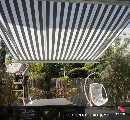סוכך פסים לבן ואפור בגינה עם שולחן וכיסאות.